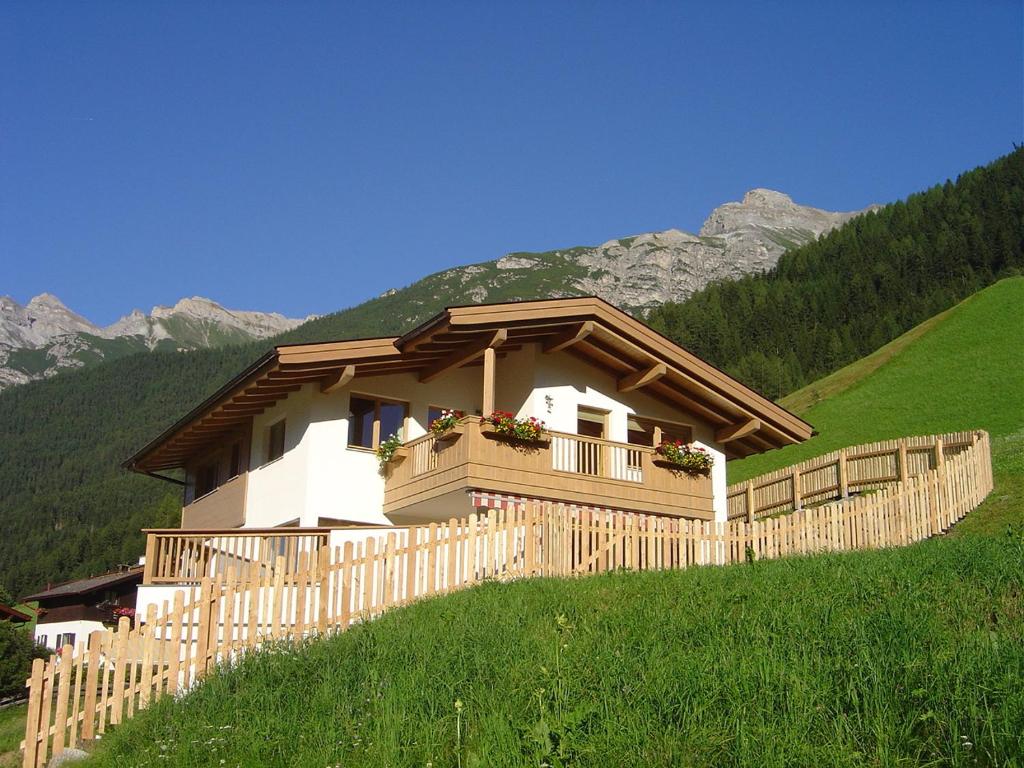 ein Haus auf einem Hügel mit einem Holzzaun in der Unterkunft Haus Harbauer in Neustift im Stubaital