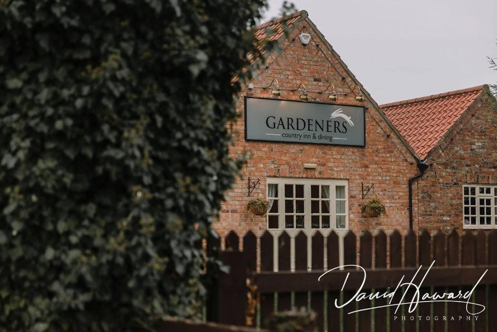 a sign on a brick building with a fence at The Gardeners Country Inn in Hull