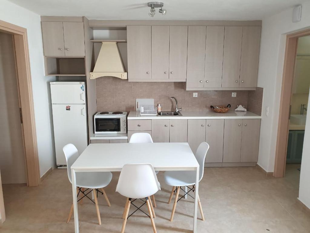 a kitchen with a white table and white chairs at Maya Apartments in Dexamenes