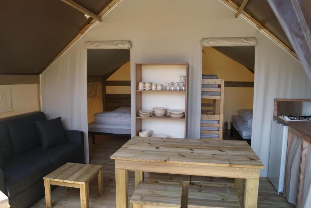 a room with a table and a couch and bunk beds at Camping de Kergo in Ploemel
