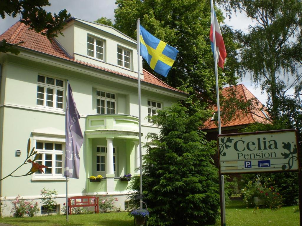 a white house with flags in front of it at Pension Celia in Wismar