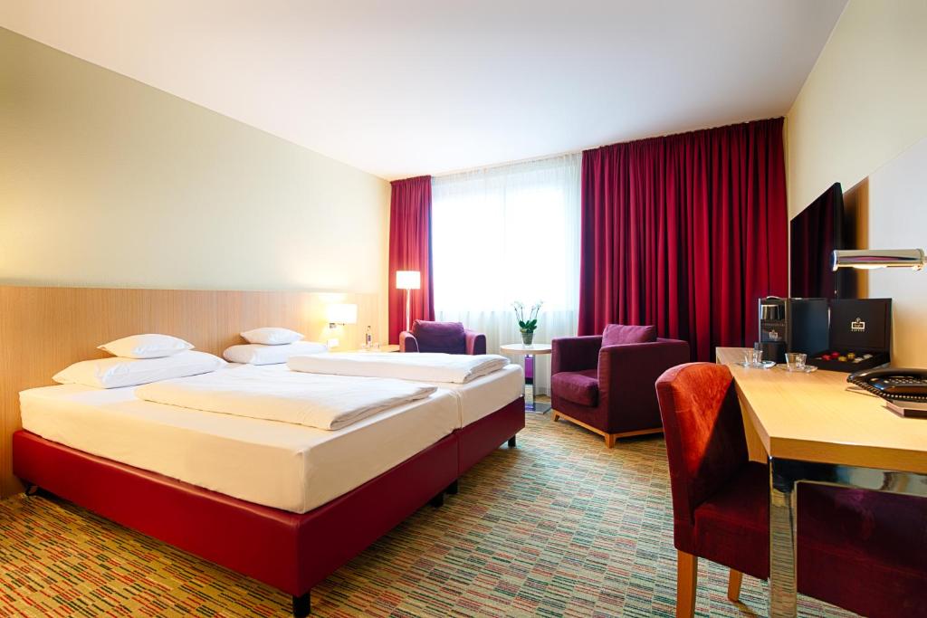 a hotel room with two beds and a desk at Welcome Hotel Paderborn in Paderborn