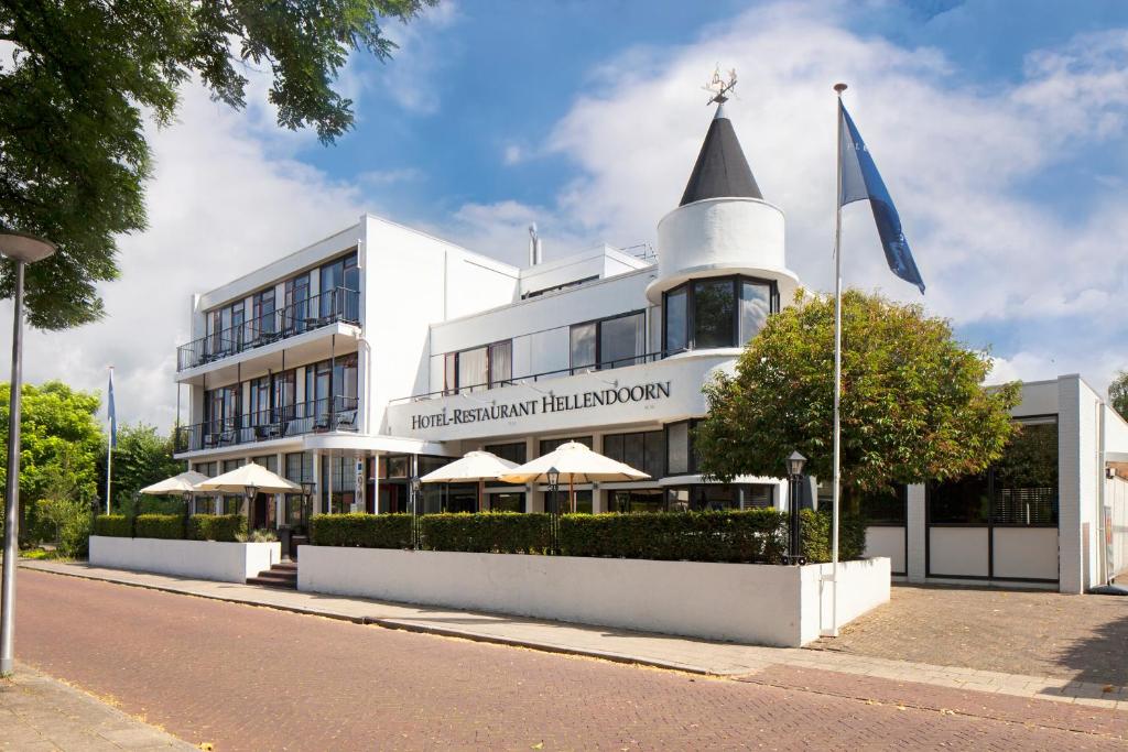 um edifício branco com um topo pontiagudo numa rua em Fletcher Hotel Restaurant Hellendoorn em Hellendoorn