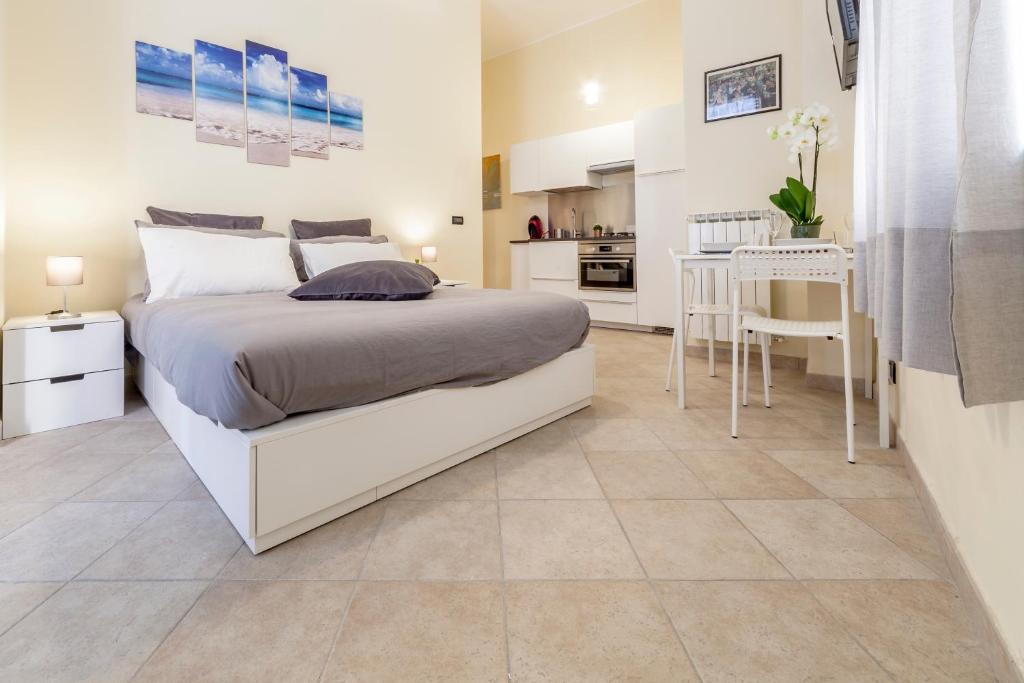 a bedroom with a white bed and a kitchen at Narciso Centralissimo in Sanremo