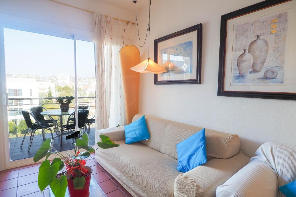 sala de estar con sofá y almohadas azules en Aquamarine Terrace Apartment by Hello Homes Sitges, en Sitges