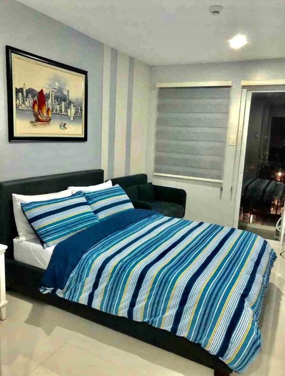 ein Schlafzimmer mit einem Bett mit blau-weißen Streifen in der Unterkunft Explorer Suite 1004 in Bacolod City