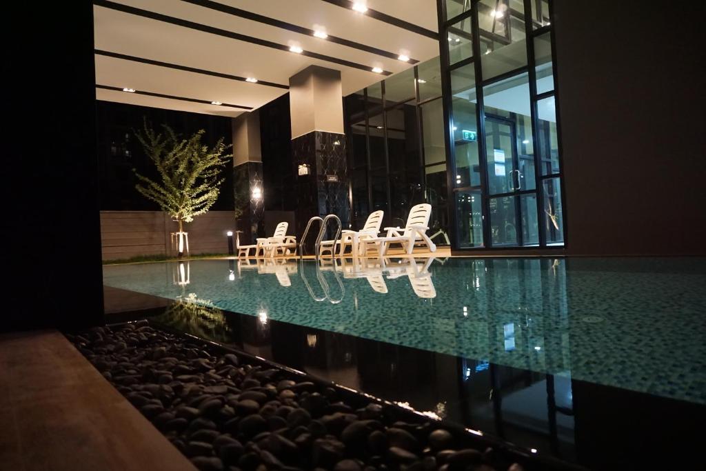 una casa con piscina e alcune sedie di MAYA宁曼路 Plam phoenix 高级公寓 a Chiang Mai
