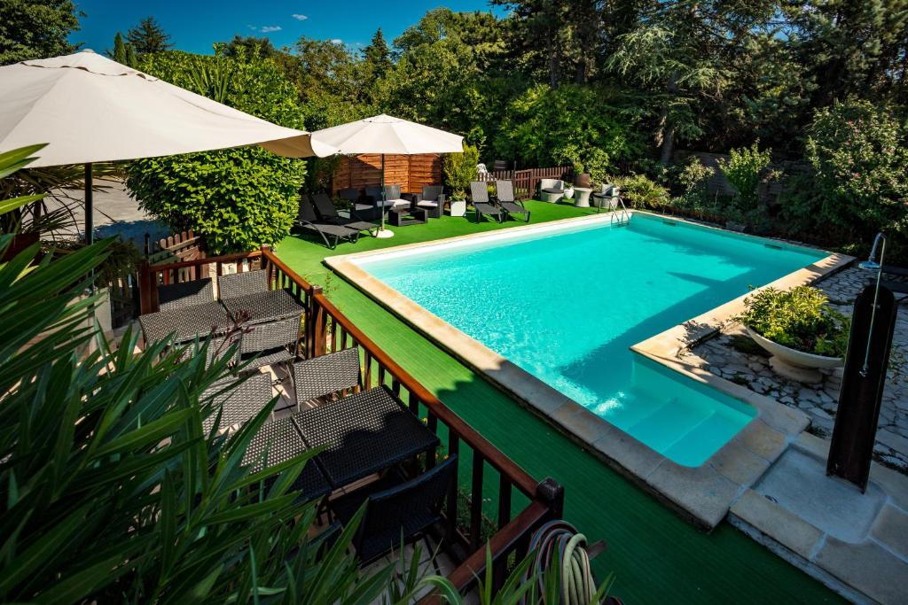 una piscina con sillas y sombrilla en LOGIS HOTEL RESTAURANT L' Auberge d'Uzes, en Uzès