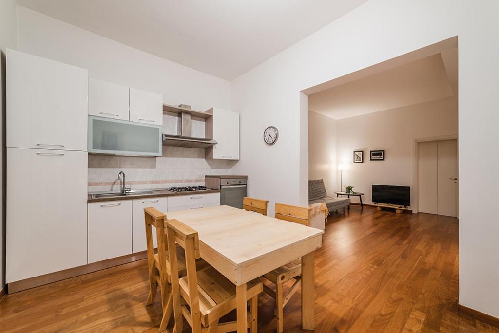 バーリにあるManzoni Houseの白いキャビネットと木製テーブル付きのキッチン