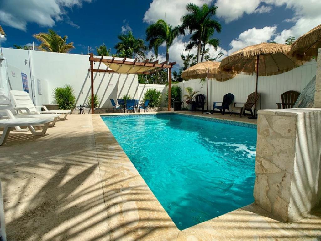 una piscina con sillas y sombrillas junto a un edificio en Blue House Joyuda, en Cabo Rojo