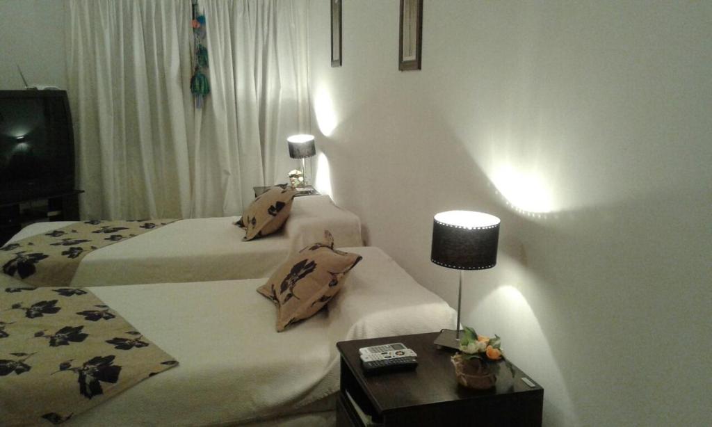 a hotel room with two beds and a table with a lamp at Buenos Aires 435 in San Miguel de Tucumán