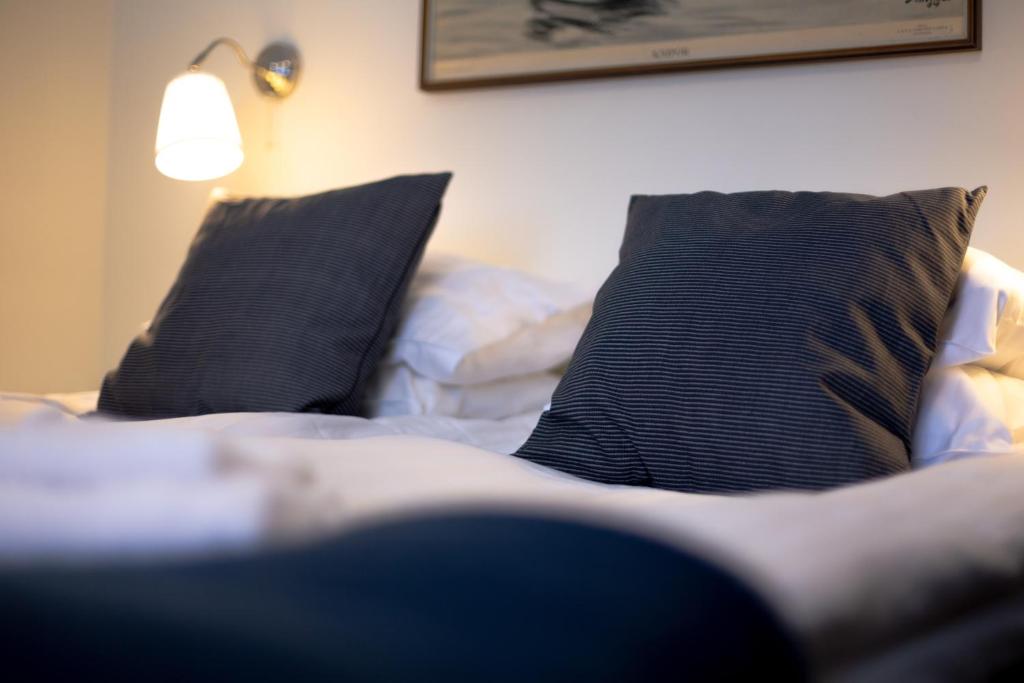 een bed met twee zwarte kussens en een lamp bij Ammarnäs Wärdshus in Ammarnäs