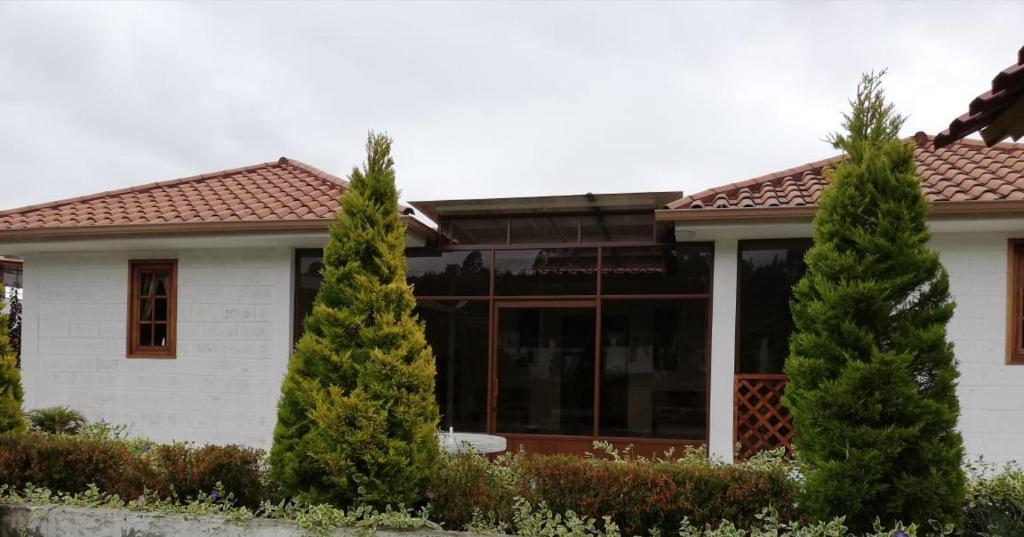 une maison avec trois arbres devant elle dans l'établissement Quinta Spa El Rosal, à Ambato