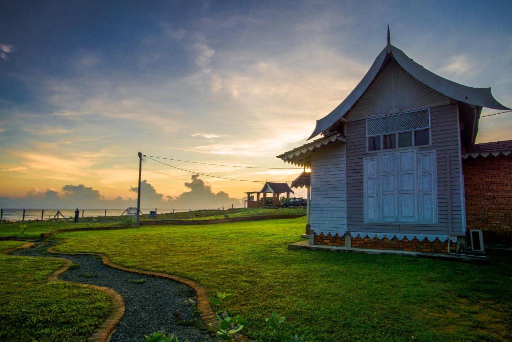 a small house with a roof on a grass field at Umbut Bayu in Dungun