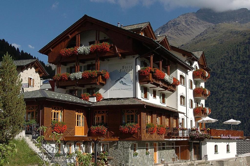 un bâtiment avec des fleurs sur les balcons d'une montagne dans l'établissement Hotel Baita Fiorita, à Santa Caterina di Valfurva