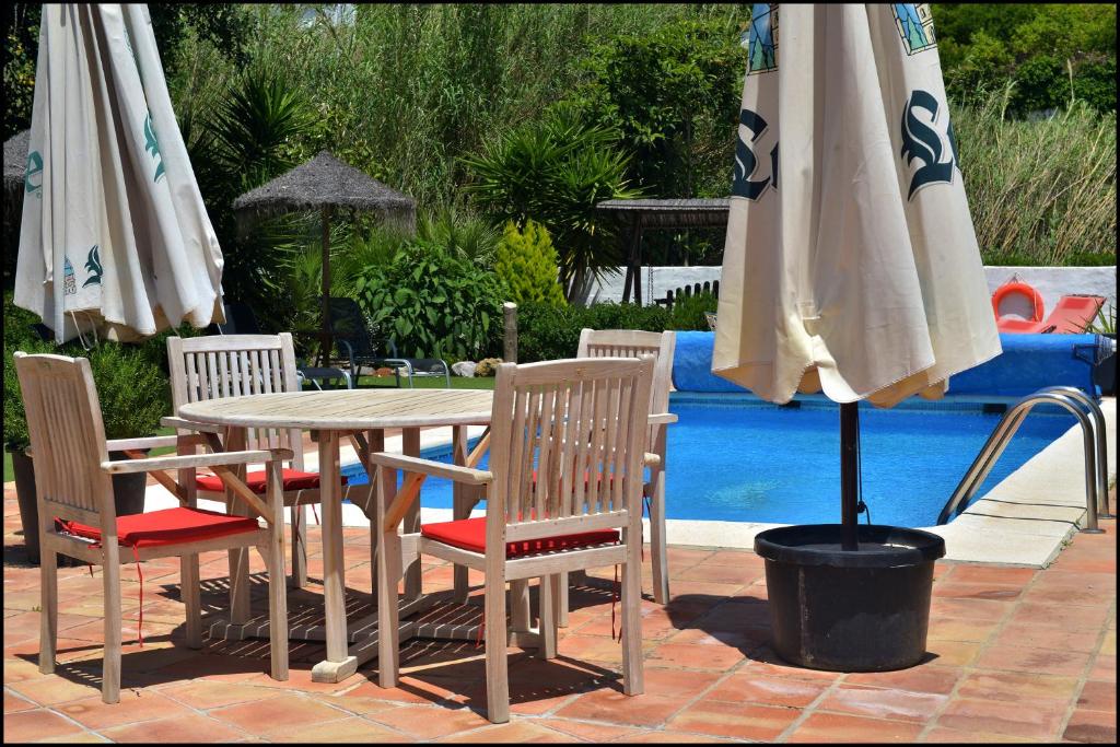 Molino de Las Tablas في Ríogordo: طاولة وكراسي مع مظلة بجوار حمام السباحة