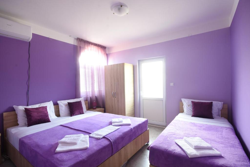 a purple room with two beds with towels on them at Apartments Astel in Bar