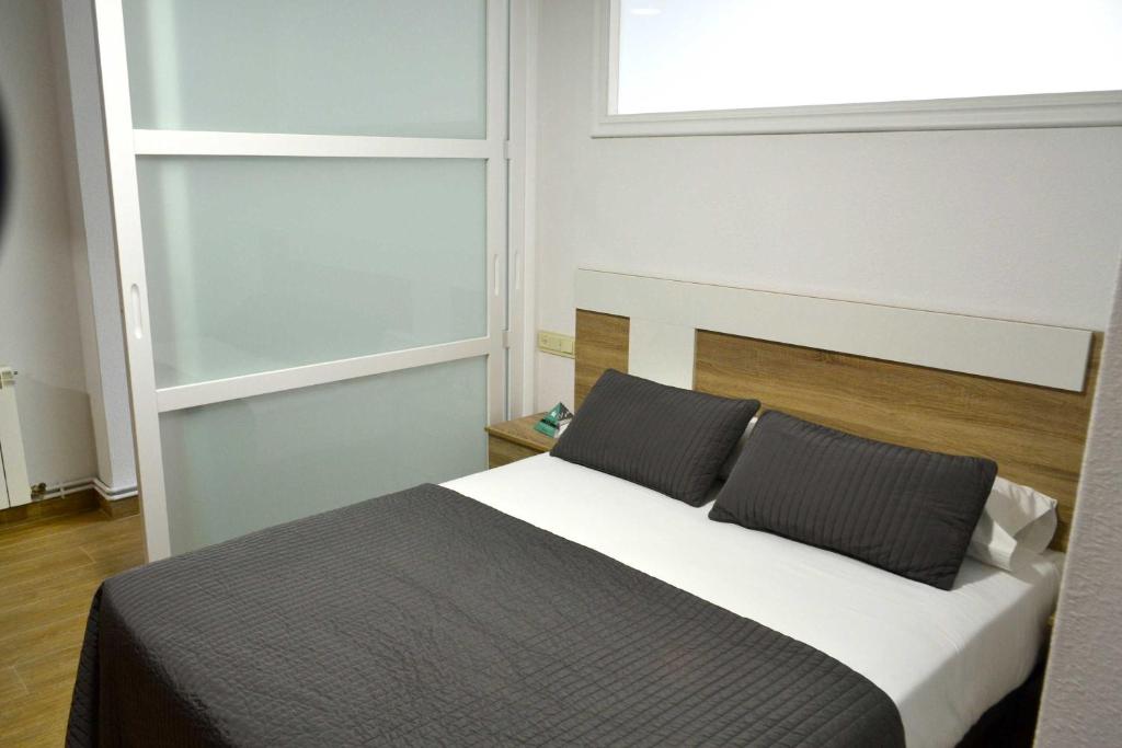 1 dormitorio con 1 cama con 2 almohadas y ventana en Apartamentos Alda Santa Cristina, en Perillo