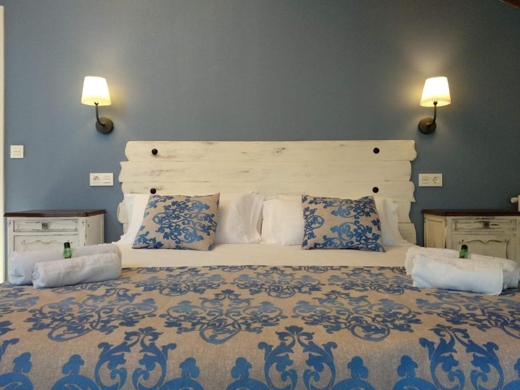 ein Schlafzimmer mit einem großen weißen Bett mit blauen und weißen Kissen in der Unterkunft Casa Rural Tierra y Madera in Barrio