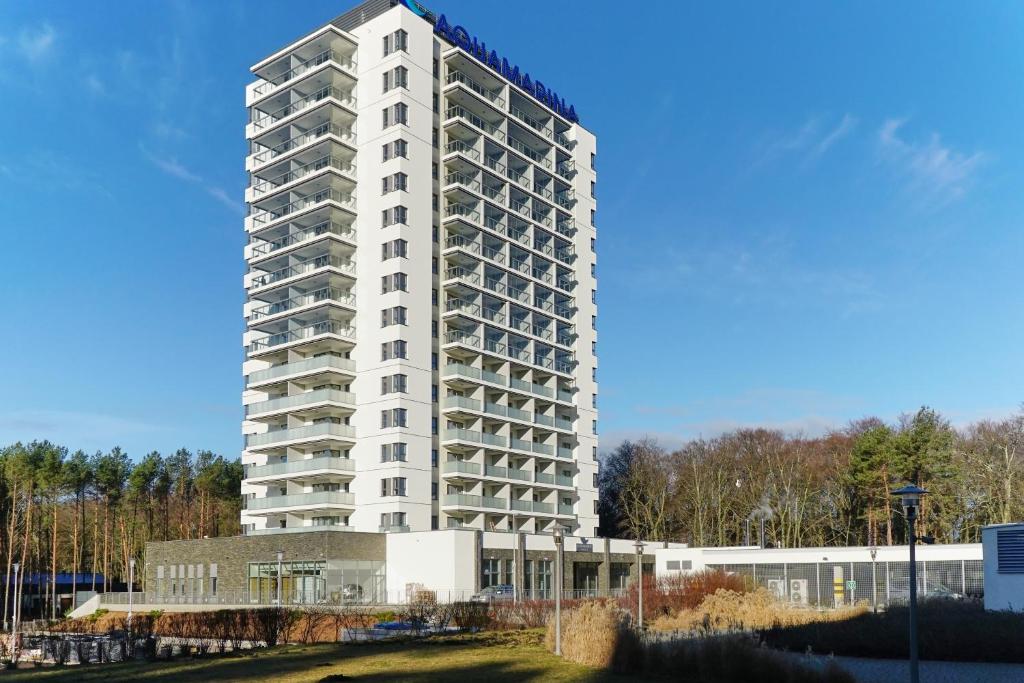 a tall white apartment building in front of a building at Aquamarina Onyx Marina Invest in Międzyzdroje