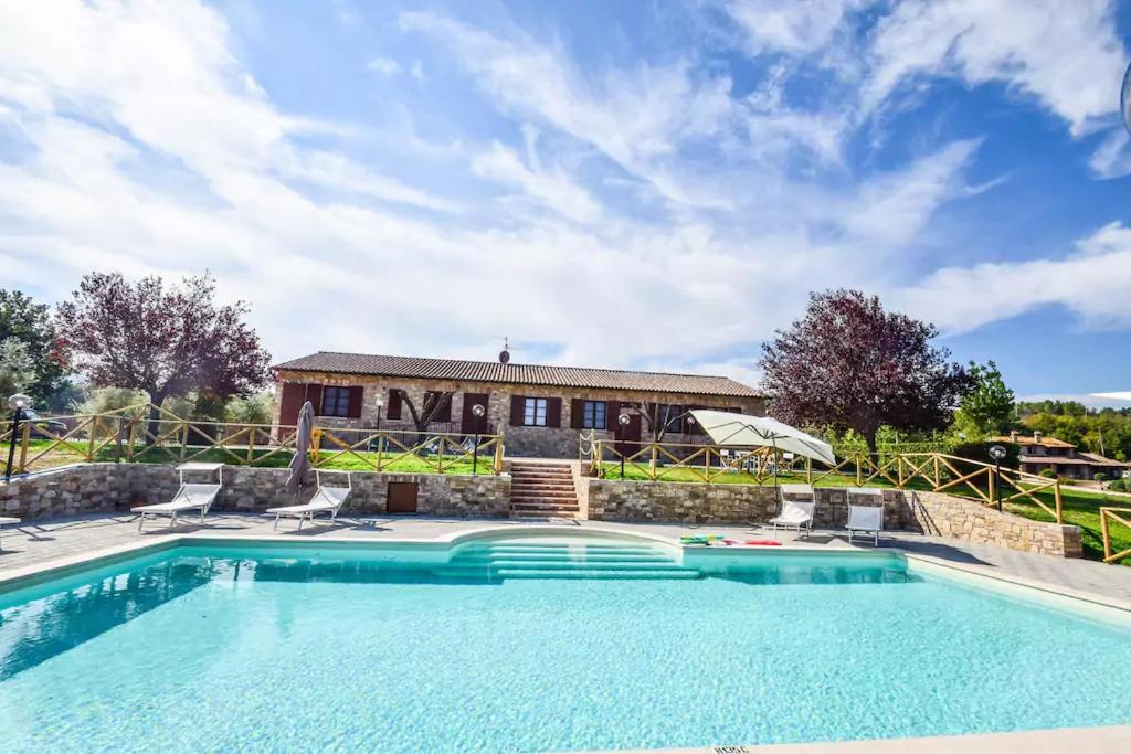 a swimming pool with chairs and a house at Agriturismo Il Falco in Todi