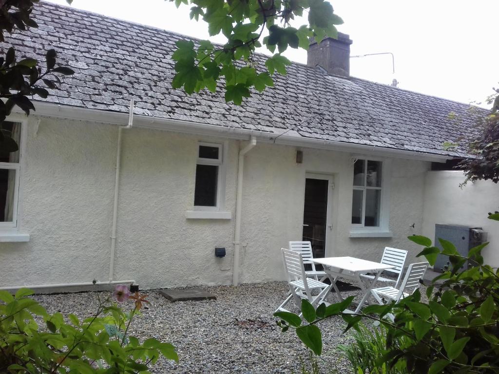 een wit huis met een tafel en stoelen ervoor bij Town House in Ennis