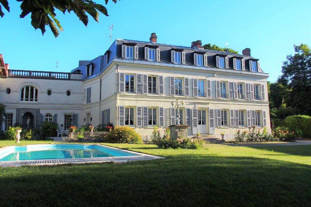 a large white house with a swimming pool in front of it at Le Clos des Fées in Asnières-sur-Oise