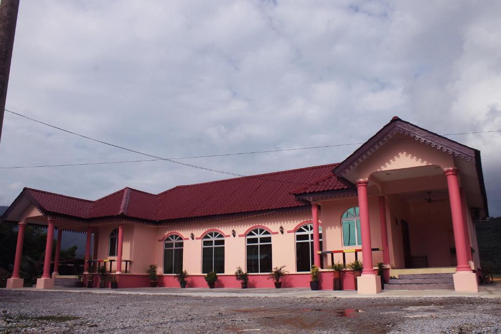 a pink building with a red roof at Malinja Home in Pantai Cenang