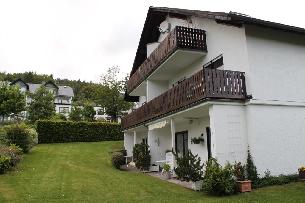 a white house with a balcony and a yard at Haus Wanderlust in Willingen