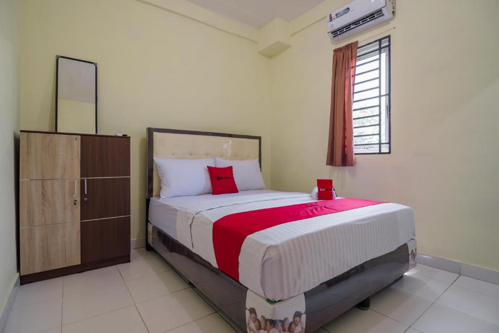 een slaapkamer met een bed, een dressoir en een raam bij RedDoorz near Politeknik Negeri Medan in Medan