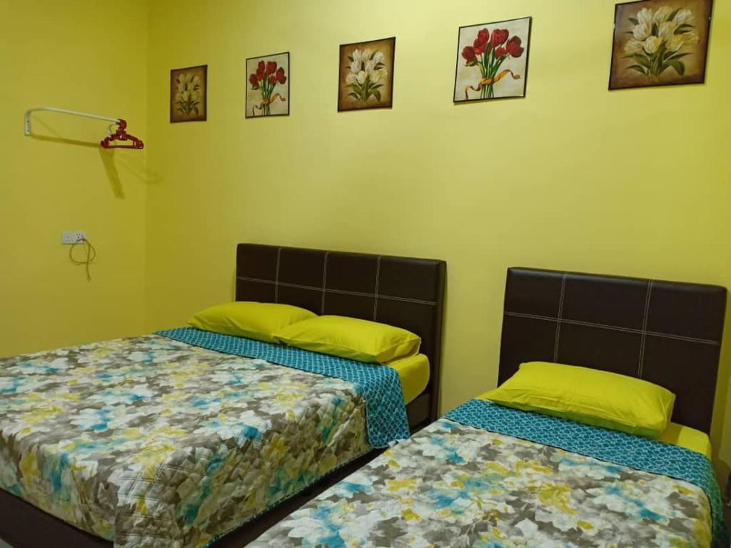 2 Betten in einem Zimmer mit gelben Wänden in der Unterkunft Mutiara Inn GuestRoom in Kampung Gurun