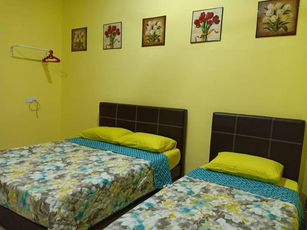 Mutiara Inn GuestRoom في Kampung Gurun: سريرين في غرفة بجدران صفراء