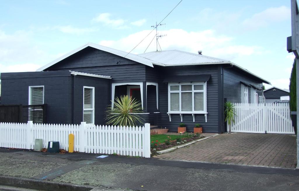 una casa negra con una cerca blanca delante de ella en Wellesbourne Homestay B&B en Palmerston North