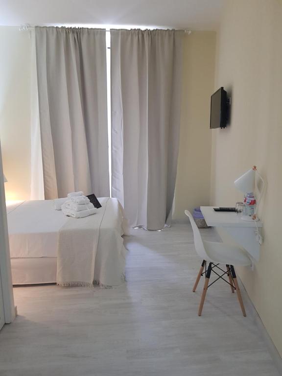 a white bedroom with a bed and a desk and a television at Le Petit Palü-Fuencarral in Madrid