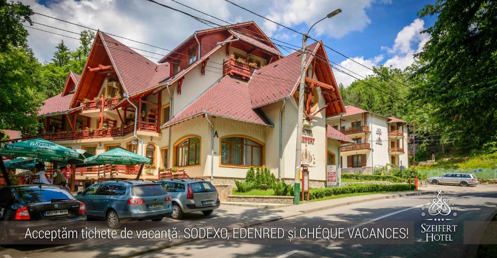 a building with cars parked in front of a street at Hotel Szeifert in Sovata