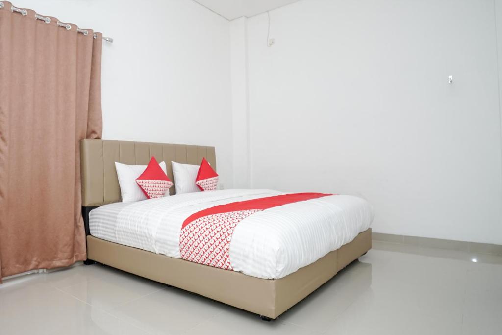 a bedroom with a bed with red and white pillows at OYO 443 Hotel Barlian in Palembang