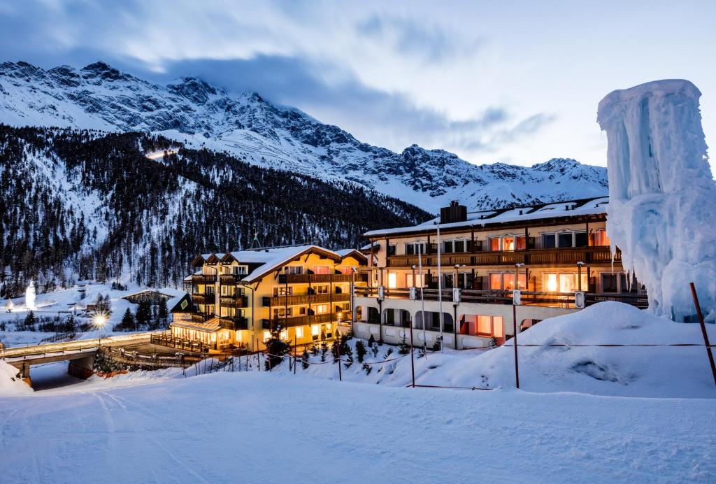 een gebouw in de sneeuw met bergen op de achtergrond bij Paradies Pure Mountain Resort in Solda