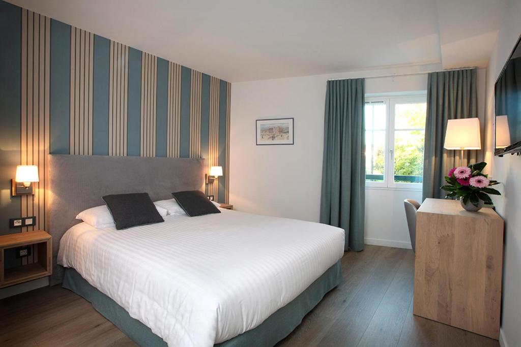 サン・ペ・シュル・ニヴェルにあるLogis Hotel de la Nivelleの大きなベッドと窓が備わるホテルルームです。