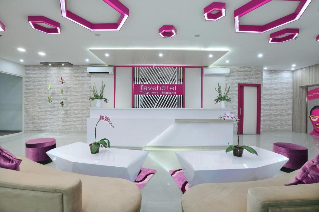 un vestíbulo con 2 mesas blancas y sillas moradas en favehotel Malang, en Malang