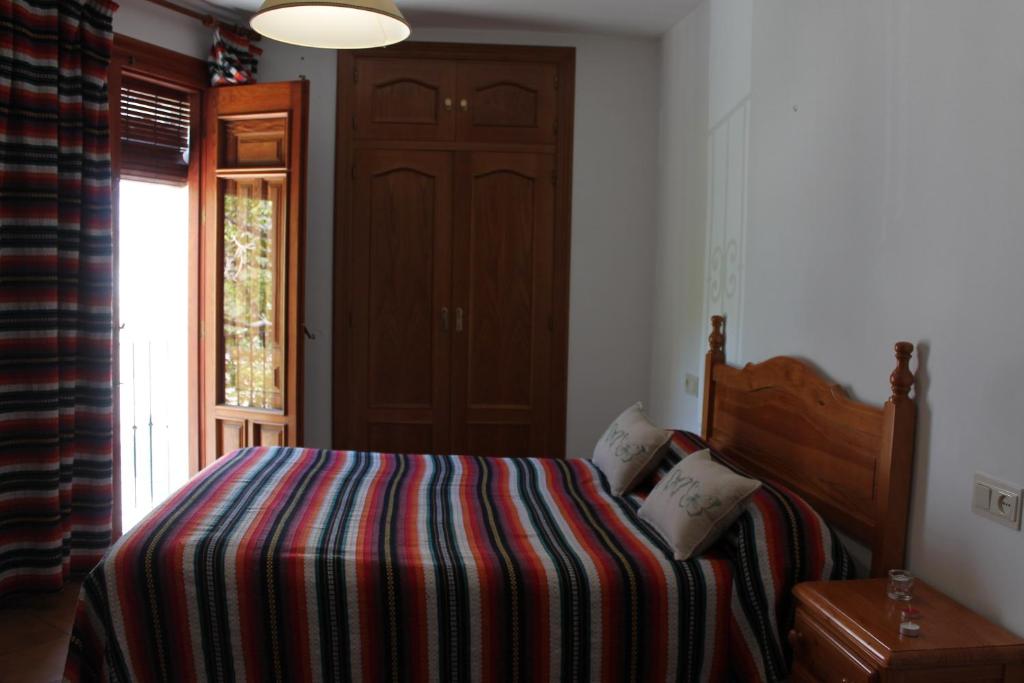 a bedroom with a bed with a striped blanket and a door at Apartamentos Rurales Rosendo: El Celindo in Capileira