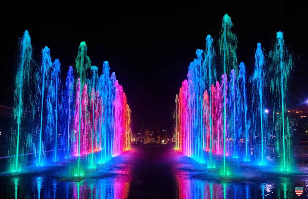 a water fountain with colorful lights in the dark at Hôtel le XIX in Béziers