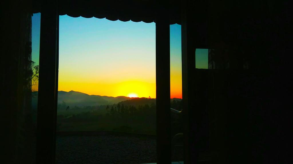 a view of the sunset from a window of a house at Chalé Vale do Ipê in Canelinha