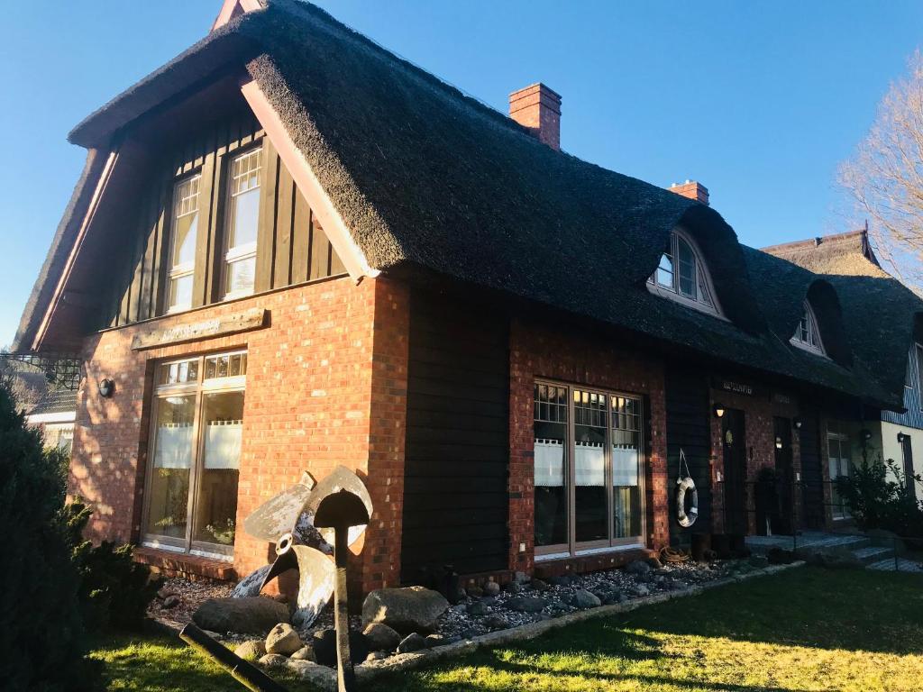 ein Haus mit einer Statue einer Person, die einen Regenschirm hält in der Unterkunft "Bootsschuppen" by Ferienhaus Strandgut in Born