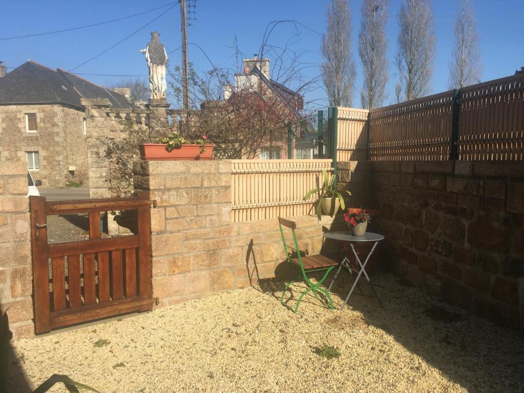 une terrasse avec une clôture, une table et une statue. dans l'établissement Jolie maison bourg de Penvenan, à Penvénan