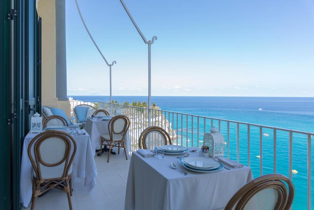 ein Restaurant mit Tischen und Stühlen auf einem Balkon in der Unterkunft Palazzo Mottola Tropea in Tropea