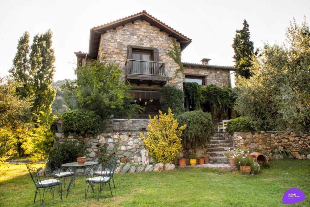 uma casa de pedra com uma mesa e cadeiras no quintal em Country House Spitaki em Velika