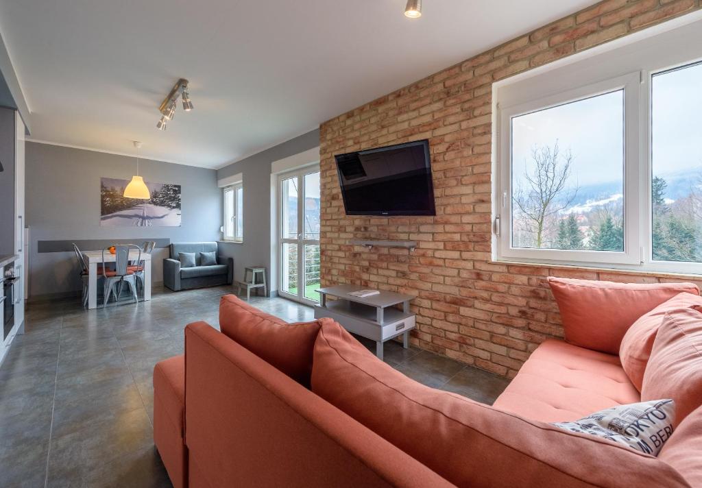 a living room with a couch and a brick wall at RentPlanet - Apartament Cicha in Świeradów-Zdrój