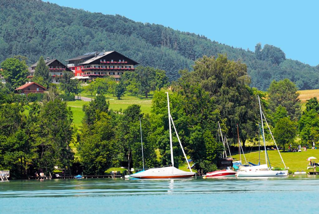 grupa łodzi na wodzie przed domem w obiekcie Hotel Haberl - Attersee w Attersee am Attersee