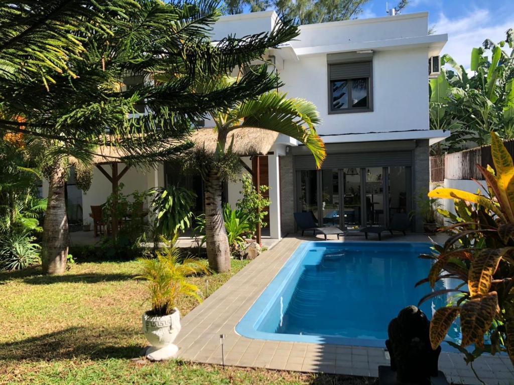 a villa with a swimming pool in front of a house at Villa North Coast in Trou aux Biches