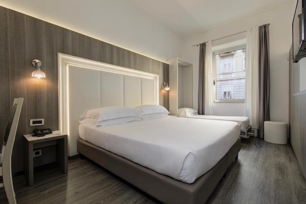 sypialnia z dużym białym łóżkiem i oknem w obiekcie Hotel San Giusto w Trieście